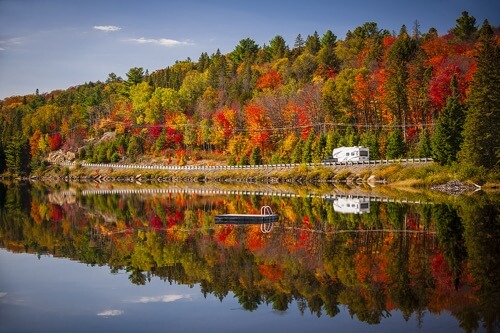 an rv traveling along a road with fall foliage