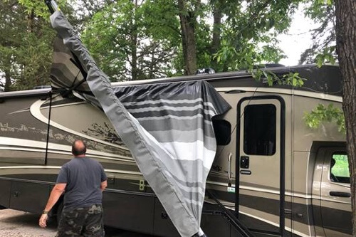 Managing RV Repair After A Storm with RV Masters in Kenner La, image of rv owner looking at rv damage to awning after storm