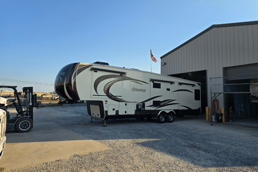 RV service package, RV repair in Laplace, LA at RV Masters. RV parked outside a metal repair facility, showcasing RV maintenance and service area with an American flag waving above the building.